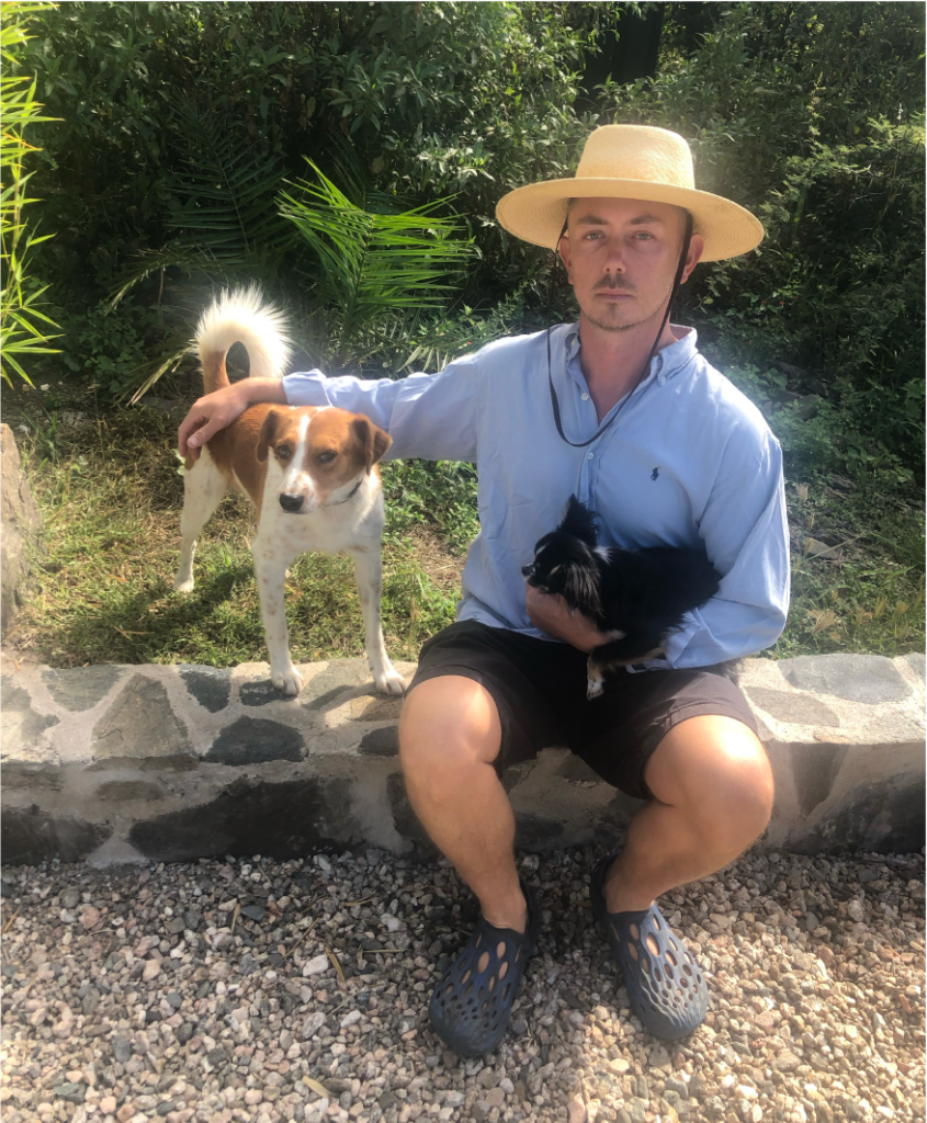 Garrett Nelson sitting on a short wall with two dogs.