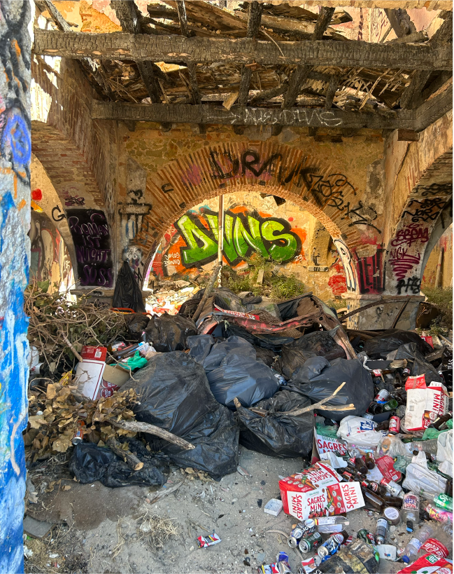 An image of a trash piled up and some grafitti on a back wall 