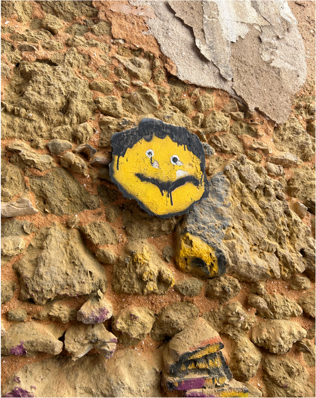 A rock wall with a face pained on one of the larger stones.