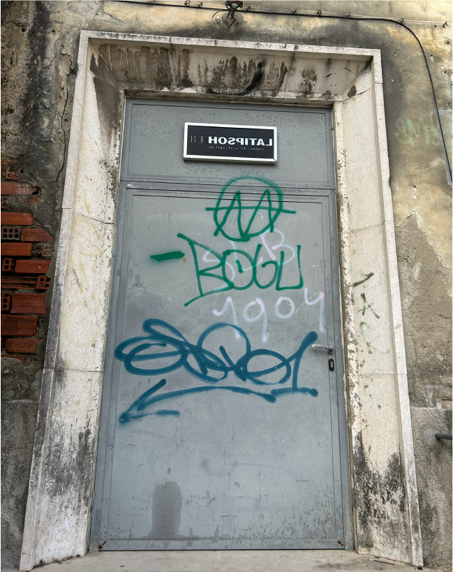 A door with the word hospital on it leading into the shell of the Miguel Bombarda hospital.