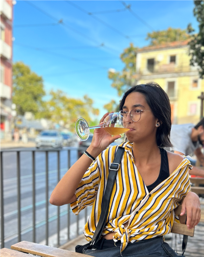 Fernanda Leme drinking wine at outdoor seating of a bar.